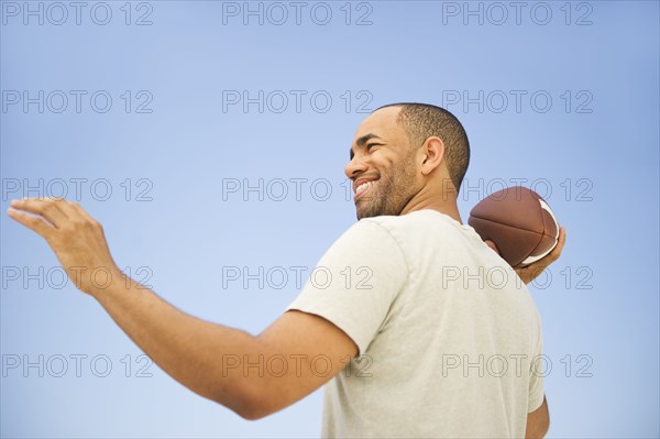 Mixed race man throwing football