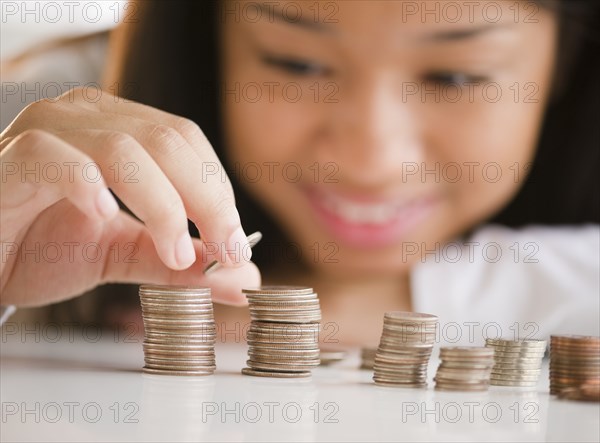 Close up of mixed race teenage girl stacking coins