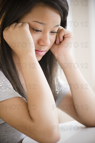 Sad mixed race teenage girl looking down with head in hands