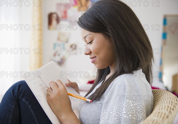 Smiling mixed race teenage girl writing in journal