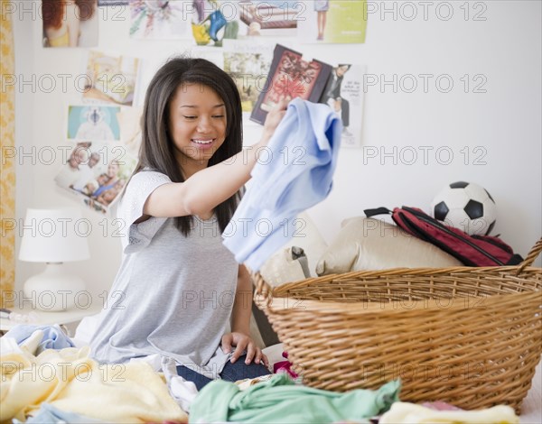 Mixed race teenage girl doing laundry on bed