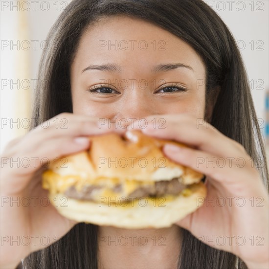 Close up of mixed race teenage girl eating cheeseburger