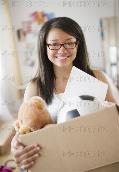 Smiling mixed race teenage girl holding box of belongings