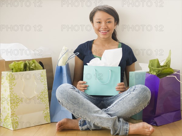 Smiling mixed race teenage girl surrounded by shopping bags