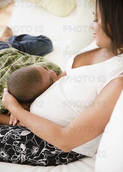 Black boy laying on pregnant mother's stomach