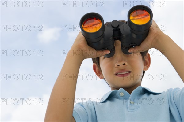 Mixed race boy looking through binoculars