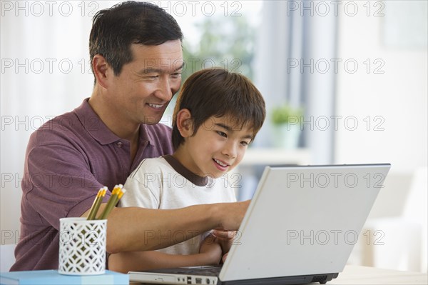 Smiling father and son using laptop