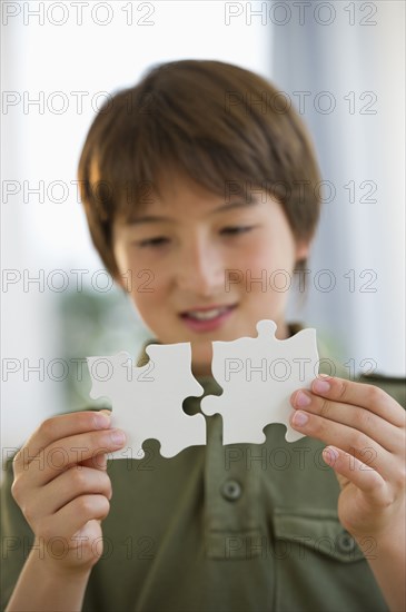 Mixed race boy connecting jigsaw pieces