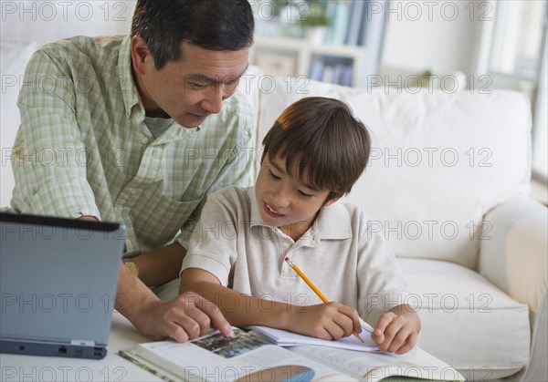 Father helping son with homework in living room