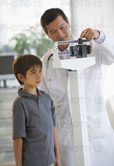 Doctor weighing boy on scale