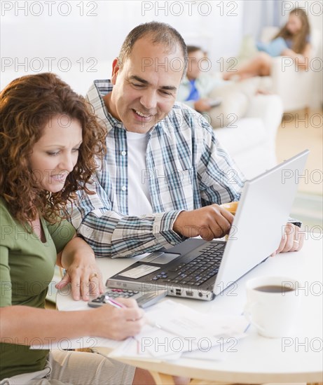 Hispanic husband and wife paying bills together using laptop