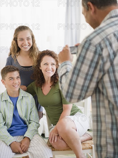 Hispanic man taking photograph of smiling family