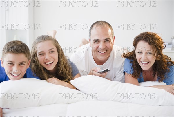 Laughing Hispanic family laying on bed together