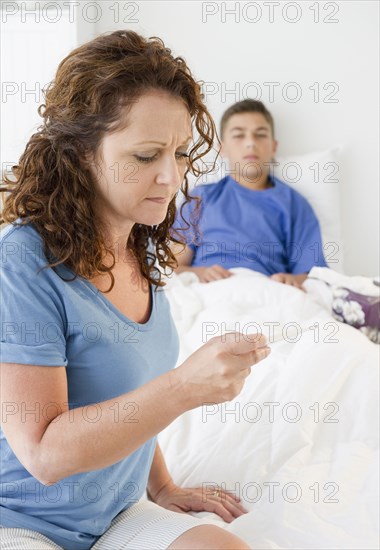 Hispanic mother taking sick son's temperature