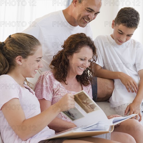 Smiling Hispanic family looking at photo album together