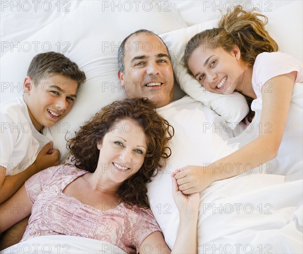 Smiling Hispanic family laying in bed together