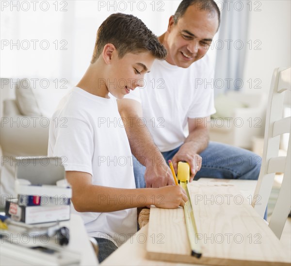 Hispanic father teaching his son carpentry