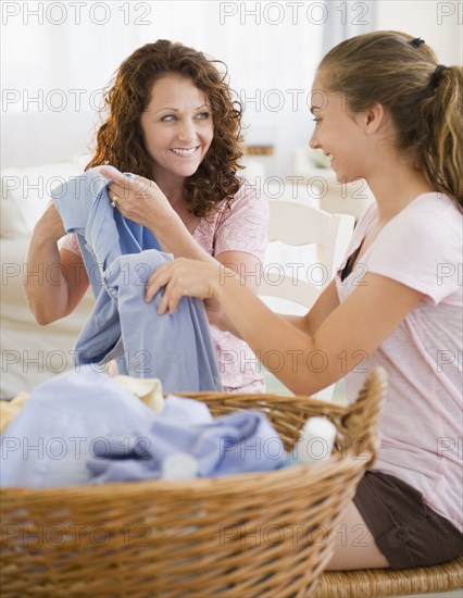 Hispanic mother and daughter folding laundry together