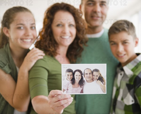 Hispanic woman with family holding out family portrait