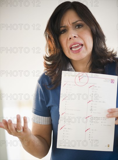 Angry Hispanic woman holding test paper with a failing grade