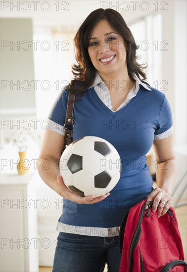 Hispanic woman holding backpack and soccer ball