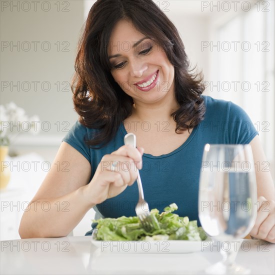 Smiling Hispanic woman eating salad for lunch