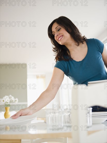 Smiling Hispanic woman setting dining table