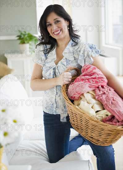 Smiling Hispanic woman carrying basket of laundry