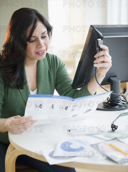 Hispanic woman reading computer assembly instructions