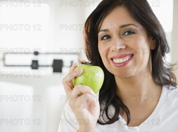 Smiling Hispanic woman holding a green apple