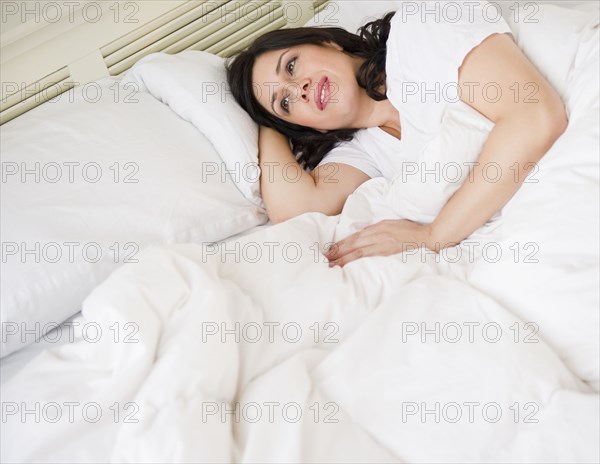 Smiling Hispanic woman laying in bed