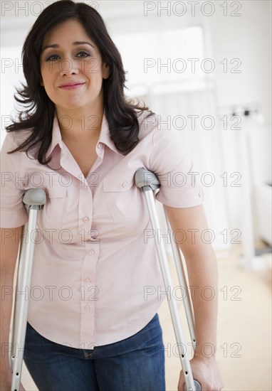 Smiling Hispanic woman walking on crutches