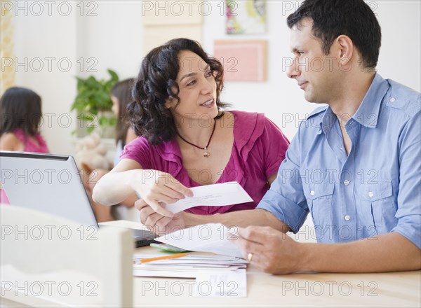 Husband and wife paying bills online with laptop