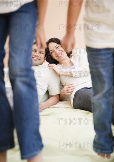 Parents watching daughters jumping on bed