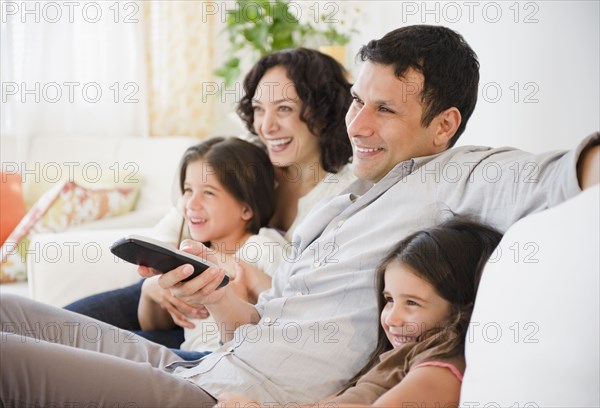 Happy family sitting on sofa watching television