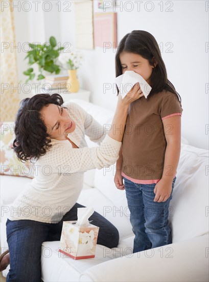 Mother wiping sick daughter's nose with tissue