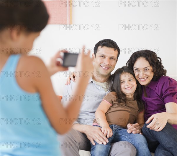 Daughter taking smiling family's photograph
