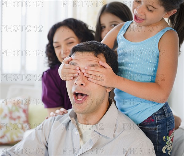 Daughter covering surprised father's eyes