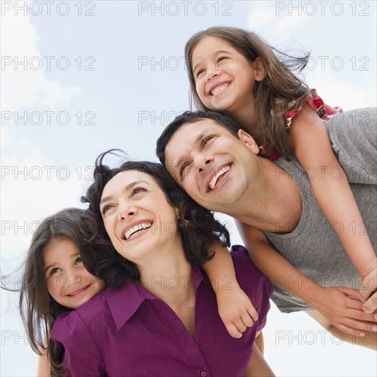 Smiling parents giving daughter's piggyback ride