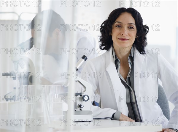 Hispanic researcher in laboratory next to microscope
