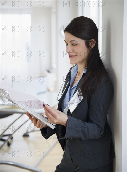 Mixed race doctor looking at medical record in hospital