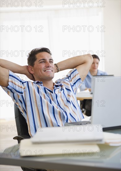 Mixed race businessman leaning back in chair at desk