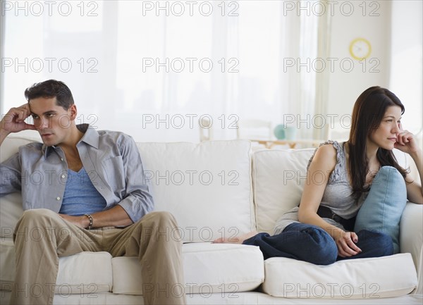 Angry mixed race couple having argument on sofa