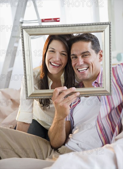 Smiling couple looking through empty frame
