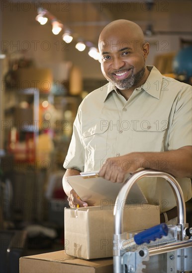 African American deliveryman with clipboard and boxes