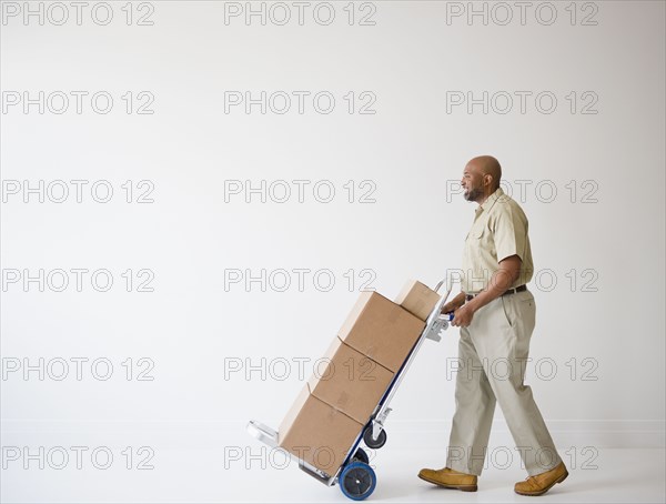 African American deliveryman pushing hand truck with boxes