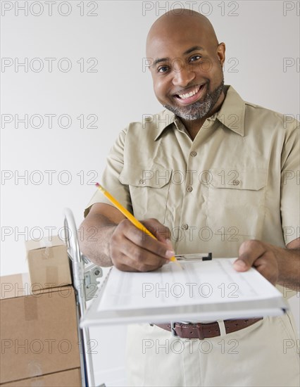 African American deliveryman holding out clipboard for signature