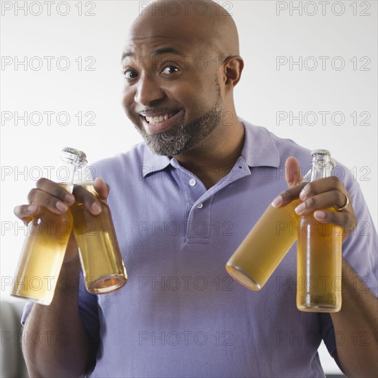 Smiling African American man holding beer bottles