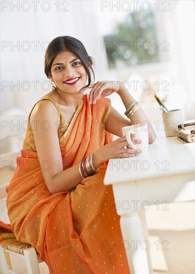 Indian woman in traditional Indian clothing drinking coffee