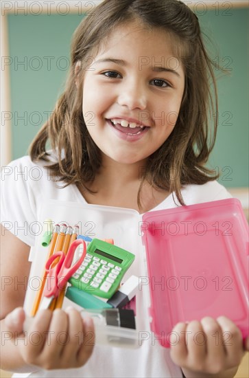 Hispanic girl holding school supplies